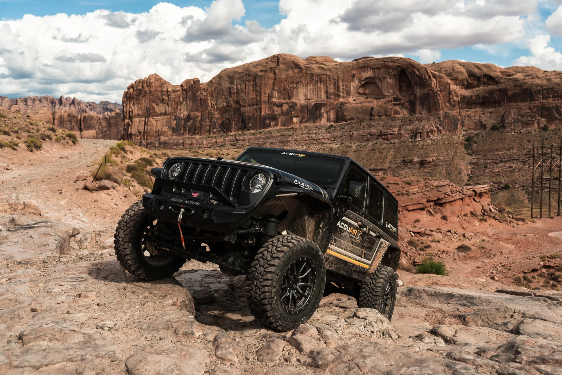 A Jeep Wrangler going off-road and rock climbing with an AccuAir air suspension upgrade.